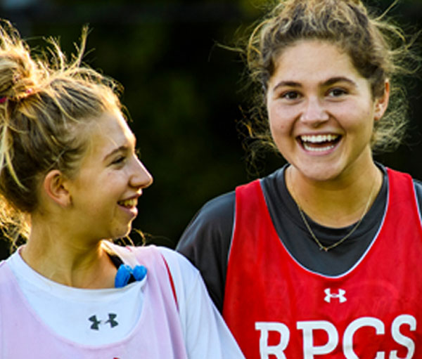 Two young smiling female athletes wearing practice pinnies