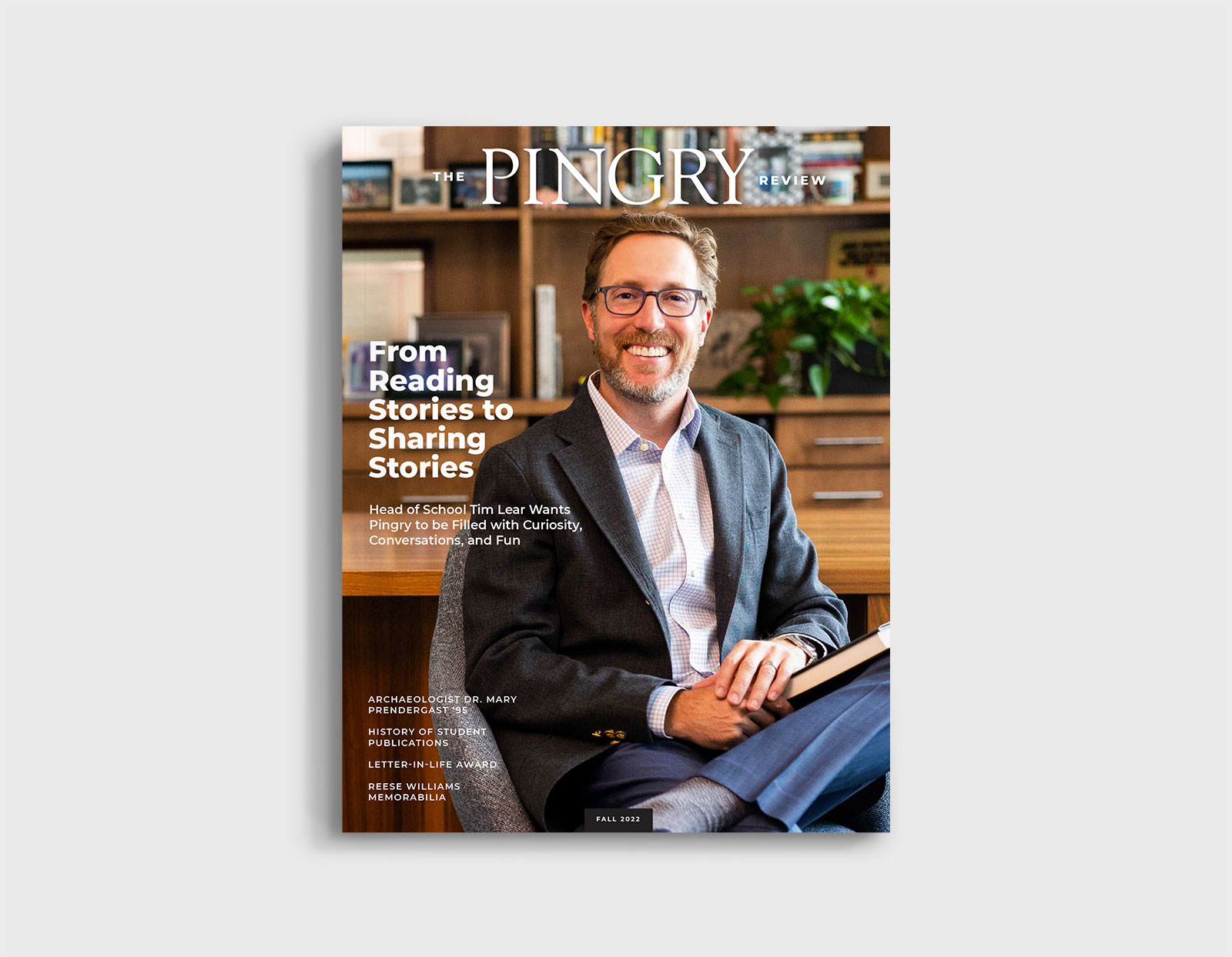 A cover of The Pingry Review featuring a young bearded white man sitting in a desk chair wearing a suit jacket