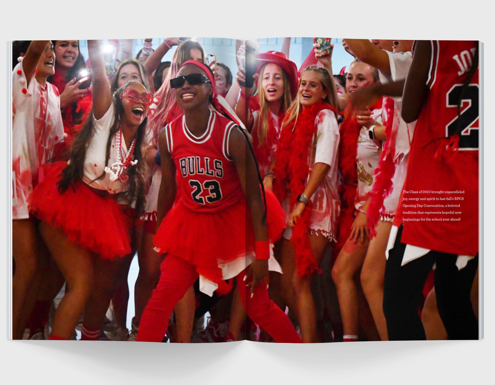 A magazine spread with a single image across both pages featuring a group of smiling, dancing teenagers all wearing red, white, and black.